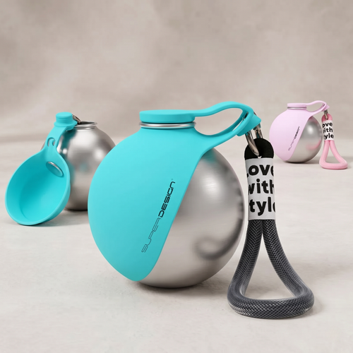 CozyPaws™ teal blue dog travel bottle with silicone bowl flipped open and ready to use — 304 stainless steel sphere body with bow print pattern and woven carry strap, pink variant visible in background