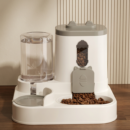 CozyPaws™ automatic 2-in-1 cat feeder grey studio shot — large transparent gravity water bottle fully filled on left, tall food storage tower with oval food-level window and cat-face dispensing gate, dry kibble in integrated food bowl, cream body on wooden surface